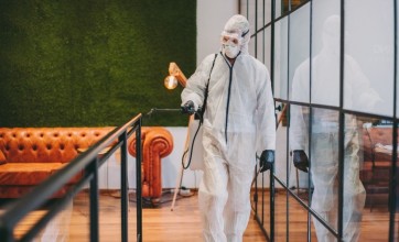 Cleaner in PPE disinfecting a space